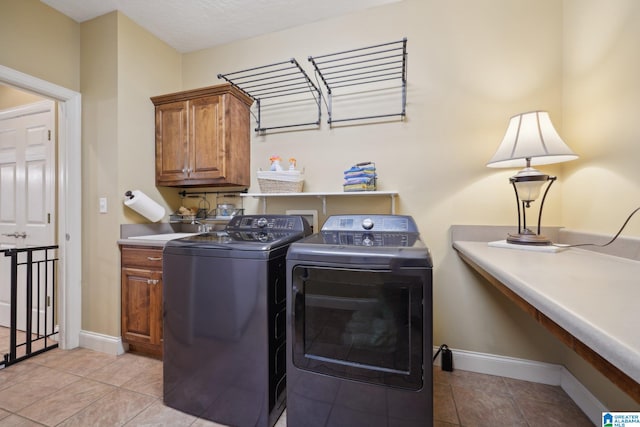 laundry area featuring sink, light tile patterned floors, washing machine and clothes dryer, a textured ceiling, and cabinets