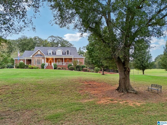 cape cod home with a front lawn and covered porch