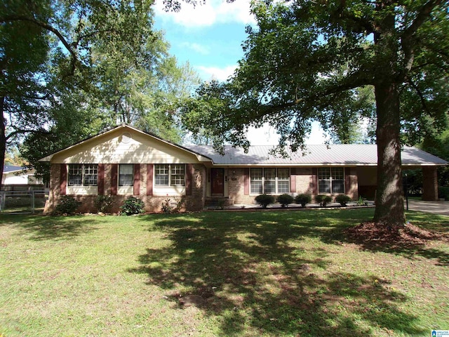 ranch-style home with a front yard, metal roof, and fence