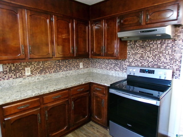 kitchen featuring light stone countertops, tasteful backsplash, electric range, under cabinet range hood, and wood finished floors