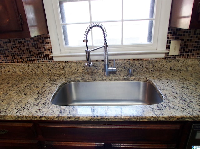room details with a sink, decorative backsplash, and light stone counters