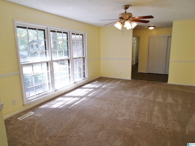 carpeted empty room with visible vents, baseboards, and ceiling fan
