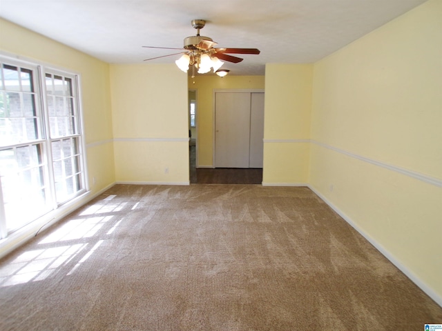empty room featuring carpet floors, a ceiling fan, and a wealth of natural light