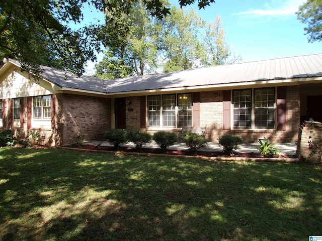 ranch-style home featuring brick siding, a front yard, and metal roof