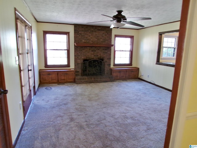 unfurnished living room featuring a ceiling fan, a textured ceiling, a fireplace, and ornamental molding