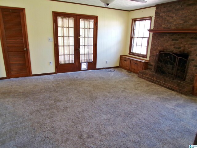 unfurnished living room with baseboards, a fireplace, french doors, crown molding, and a ceiling fan