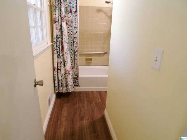 corridor featuring visible vents, baseboards, and wood finished floors