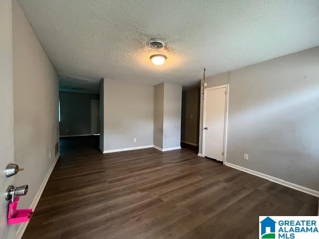 empty room with a textured ceiling and dark wood-type flooring