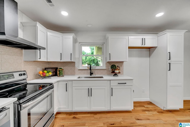 kitchen featuring light hardwood / wood-style floors, appliances with stainless steel finishes, wall chimney range hood, and sink