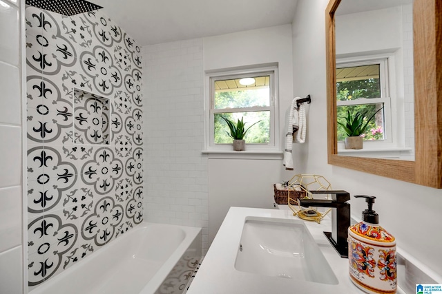 bathroom with tiled shower / bath combo, plenty of natural light, and vanity