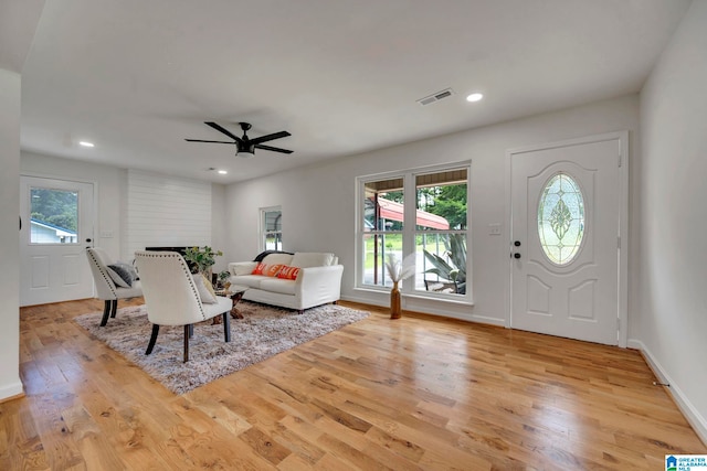 foyer entrance featuring ceiling fan, a fireplace, light hardwood / wood-style floors, and a healthy amount of sunlight