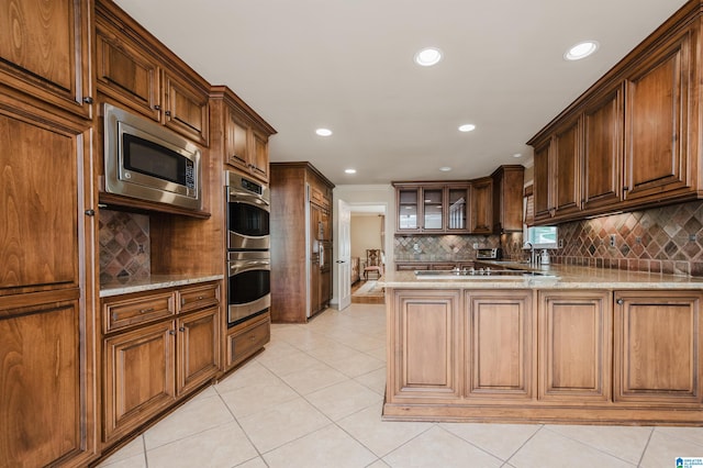 kitchen featuring decorative backsplash, stainless steel appliances, kitchen peninsula, and light tile patterned floors