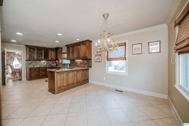 kitchen with light tile patterned flooring, kitchen peninsula, backsplash, a chandelier, and crown molding