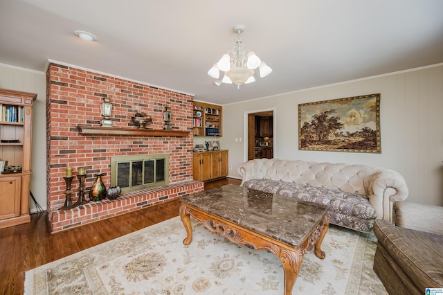 living room featuring a chandelier, a fireplace, dark wood-type flooring, and crown molding