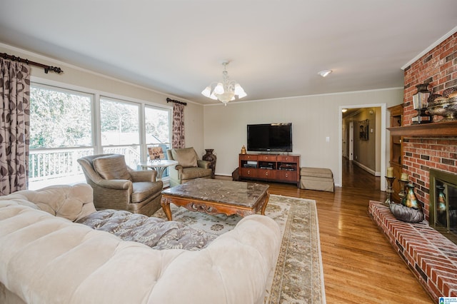 living room with light hardwood / wood-style floors, ornamental molding, an inviting chandelier, and a fireplace