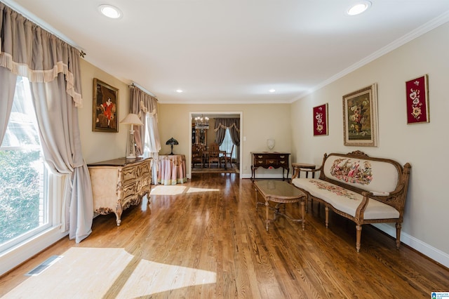 sitting room with ornamental molding, wood-type flooring, and a notable chandelier