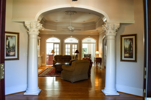 living room with dark hardwood / wood-style flooring, decorative columns, a tray ceiling, and a wealth of natural light