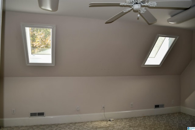 additional living space featuring ceiling fan, vaulted ceiling with skylight, and carpet floors