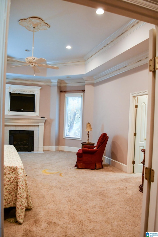 interior space featuring crown molding, carpet floors, a tiled fireplace, and ceiling fan