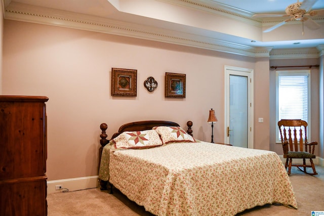 carpeted bedroom with crown molding, a tray ceiling, and ceiling fan