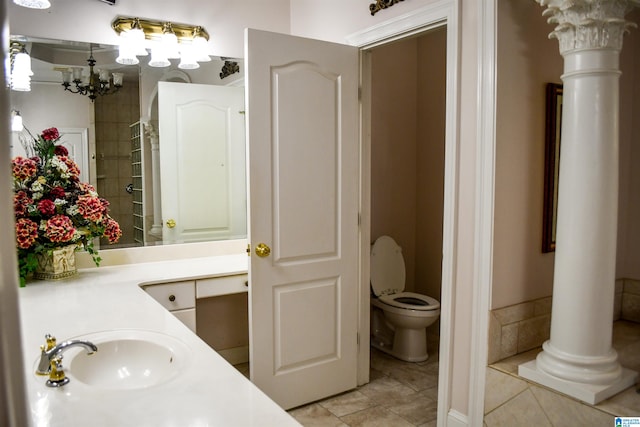 bathroom with an inviting chandelier, vanity, toilet, and tile patterned flooring