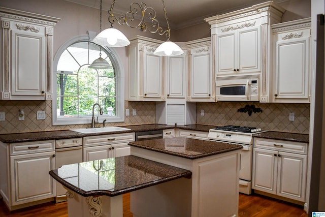 kitchen with white appliances, sink, a center island, hanging light fixtures, and decorative backsplash