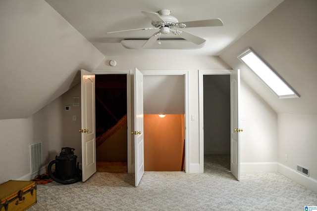 bonus room with vaulted ceiling with skylight, light carpet, and ceiling fan