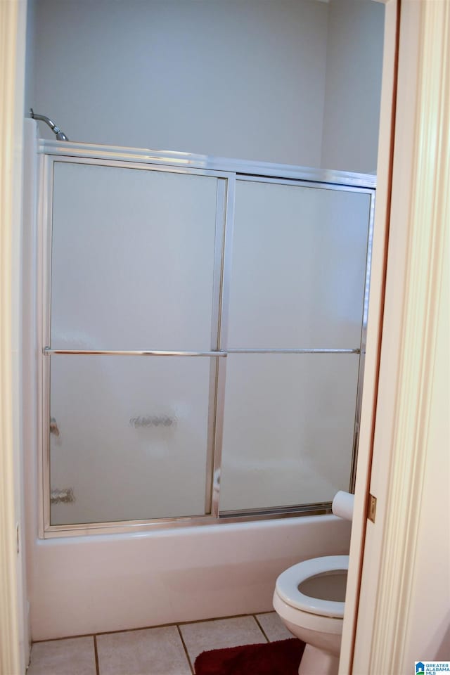 bathroom featuring bath / shower combo with glass door, toilet, and tile patterned flooring