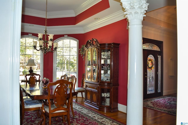 dining room featuring dark wood-type flooring, ornate columns, ornamental molding, and a chandelier