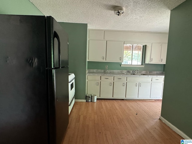 kitchen featuring white cabinets, black refrigerator, a textured ceiling, light hardwood / wood-style flooring, and white range with electric cooktop