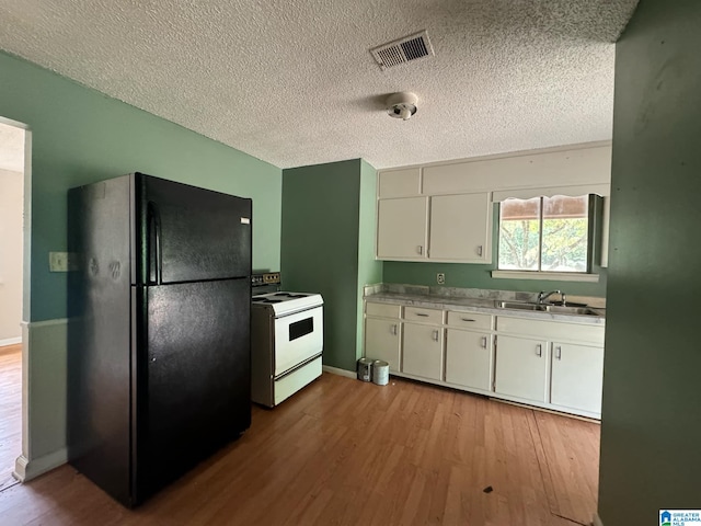 kitchen with white electric range oven, sink, black refrigerator, white cabinetry, and light hardwood / wood-style floors