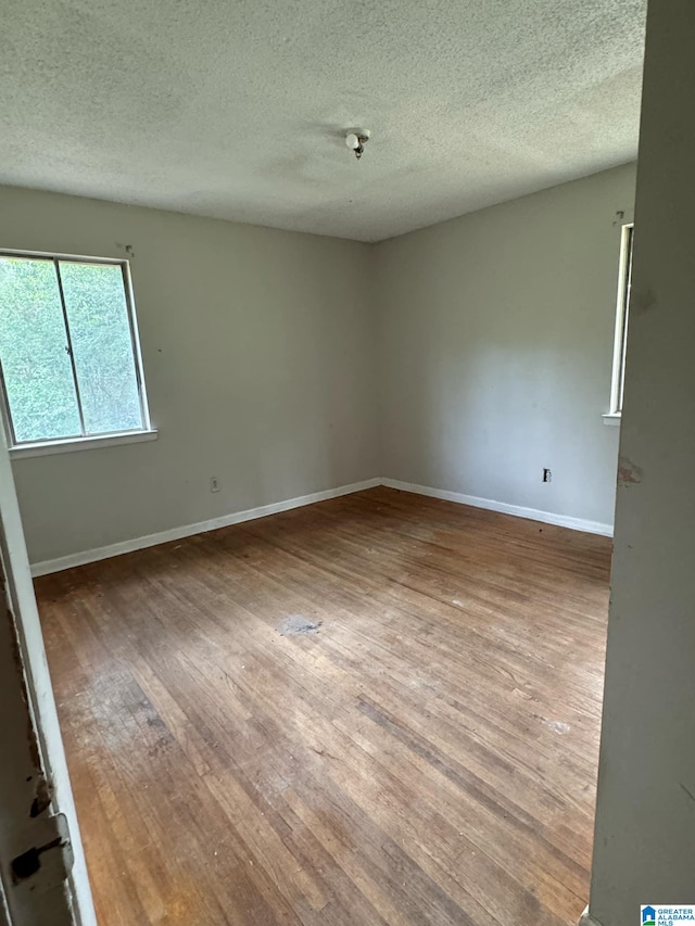 unfurnished room featuring wood-type flooring and a textured ceiling