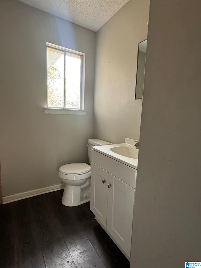 bathroom featuring hardwood / wood-style floors, a textured ceiling, vanity, and toilet