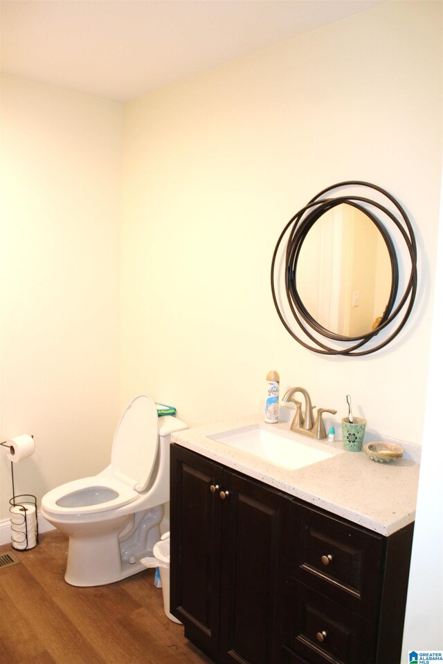 bathroom featuring wood-type flooring, vanity, and toilet