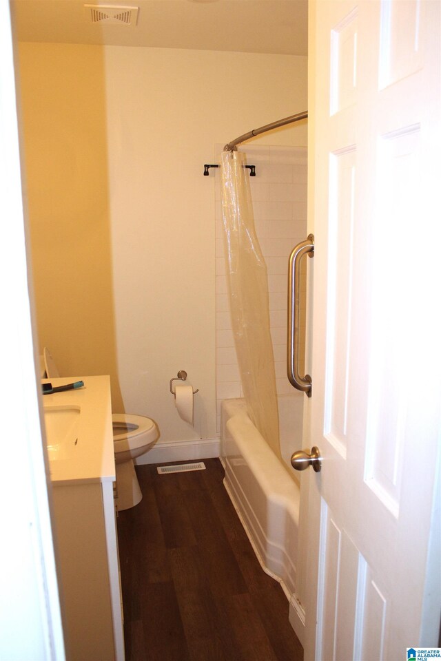 full bathroom featuring shower / bath combination with curtain, hardwood / wood-style flooring, vanity, and toilet