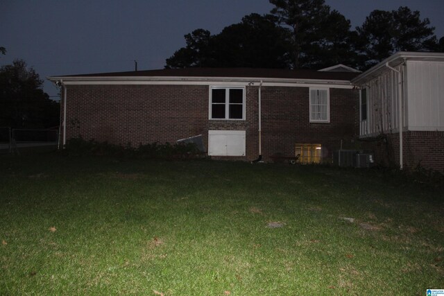 back house at twilight with a yard and central AC