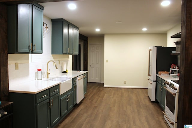 kitchen featuring tasteful backsplash, white appliances, range hood, dark hardwood / wood-style floors, and sink