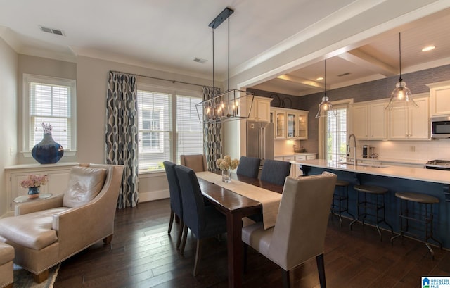 dining area featuring dark wood-type flooring, sink, a notable chandelier, and ornamental molding