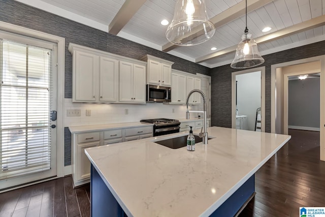 kitchen featuring stainless steel appliances, decorative light fixtures, and an island with sink