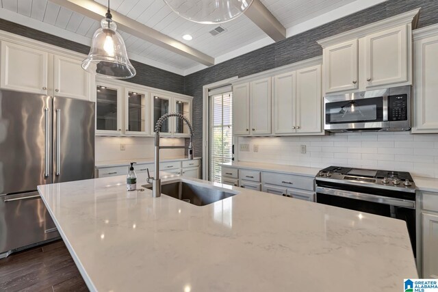 kitchen with stainless steel appliances, beam ceiling, dark hardwood / wood-style flooring, light stone countertops, and hanging light fixtures