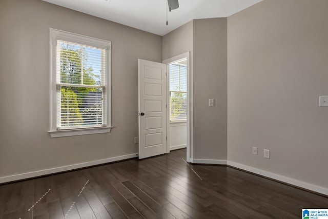 empty room featuring a wealth of natural light, ceiling fan, and dark hardwood / wood-style flooring