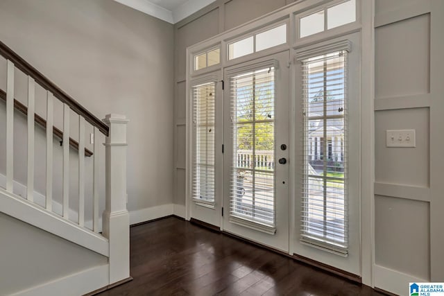 foyer entrance with ornamental molding and dark hardwood / wood-style floors