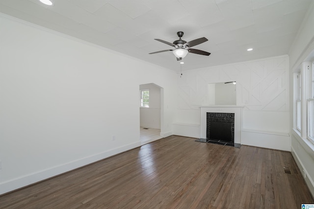 unfurnished living room with baseboards, a fireplace with raised hearth, visible vents, ceiling fan, and wood finished floors