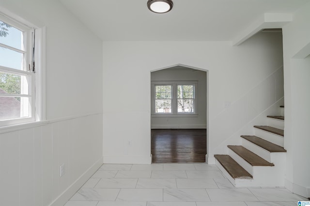 interior space featuring stairs, marble finish floor, and a wainscoted wall