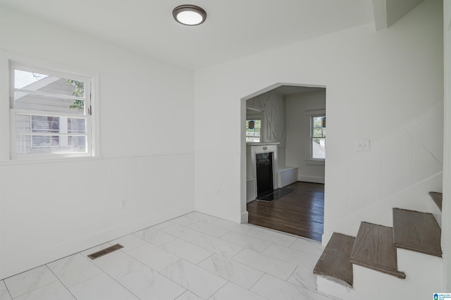 empty room with visible vents, baseboards, arched walkways, stairs, and marble finish floor
