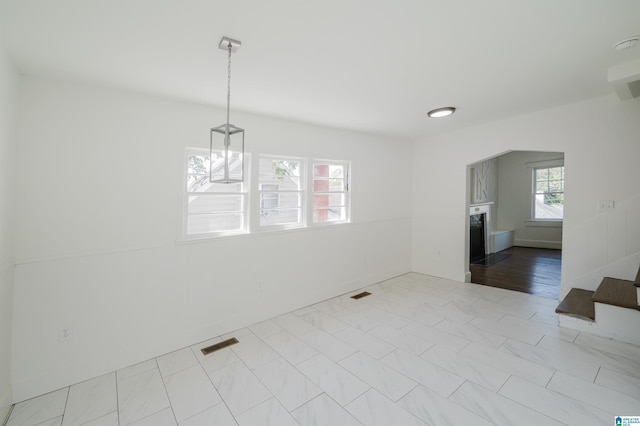 unfurnished dining area with arched walkways, baseboards, and visible vents
