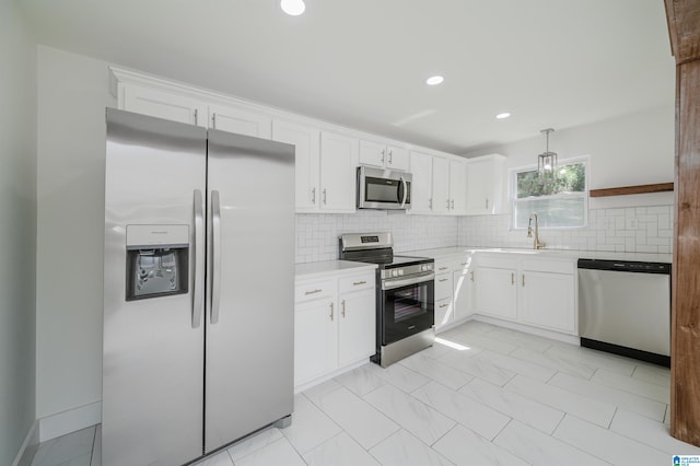 kitchen with appliances with stainless steel finishes, white cabinetry, backsplash, decorative light fixtures, and sink