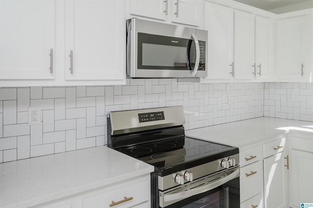 kitchen with light stone countertops, white cabinets, backsplash, and appliances with stainless steel finishes