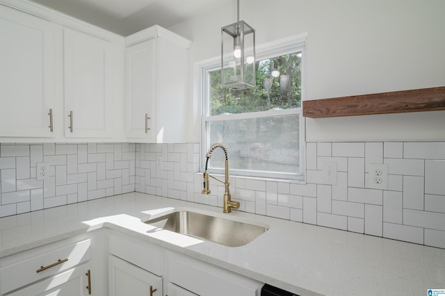 kitchen with decorative light fixtures, a sink, and white cabinetry