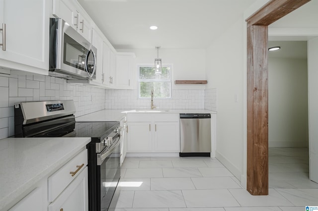 kitchen with tasteful backsplash, light stone counters, white cabinets, appliances with stainless steel finishes, and a sink